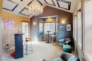 Ein Raum mit einer Neonreklame, einem Chandelier und einer Bar, komplett mit Sitzgelegenheiten.