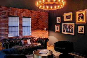 Ein gemütliches Wohnzimmer mit Backsteinwand, Ledersofa, einem runden Couchtisch und gerahmten Bildern an der Wand.