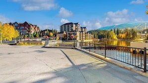 Un hotel lungo il fiume con un ponte, diversi edifici e una montagna sullo sfondo.
