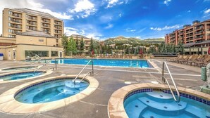 Ett hotell med ett poolområde, flera swimmingpooler och en bergig bakgrund.
