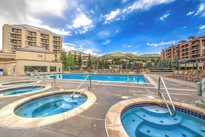 A hotel with a pool area, multiple swimming pools, and a mountainous backdrop. - Downtown studio near QuickSilver Super Chair with pool, hot tubs & fireplace (Breckenridge)