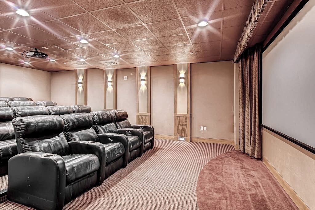 Een bioscoopzaal met leren loungestoelen, een vloerbedekking en een groot scherm.