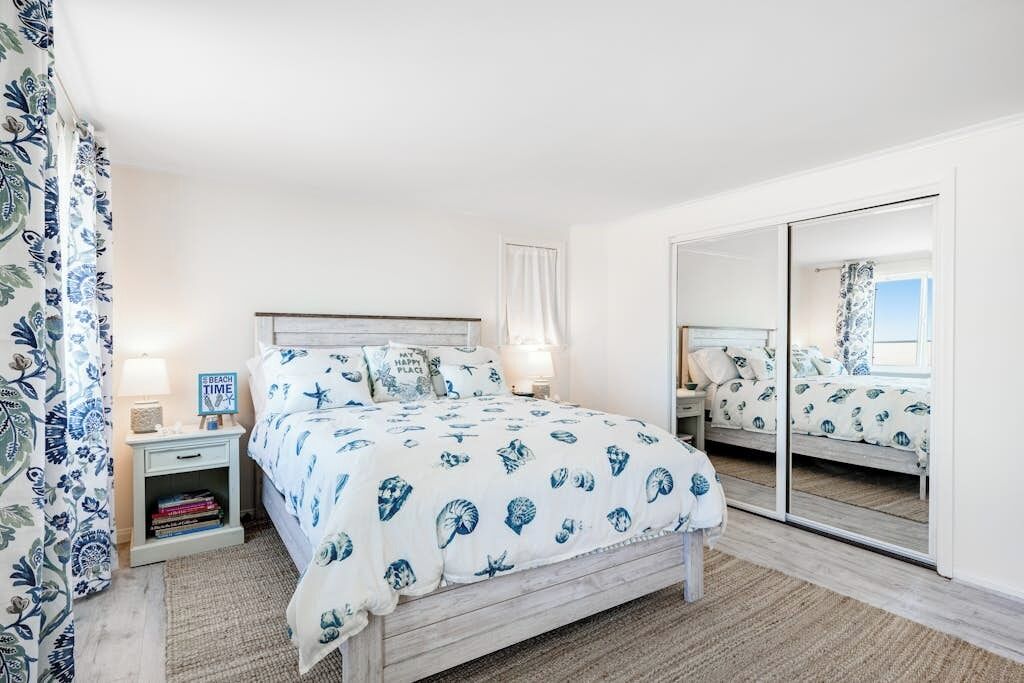 Een slaapkamer met een bed, nachtkastjes, een spiegel en uitzicht.