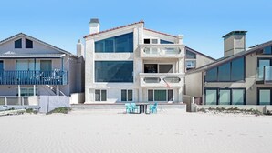 En fastighet vid stranden med en byggnad i flera våningar, en balkong och ett sandstrandområde.