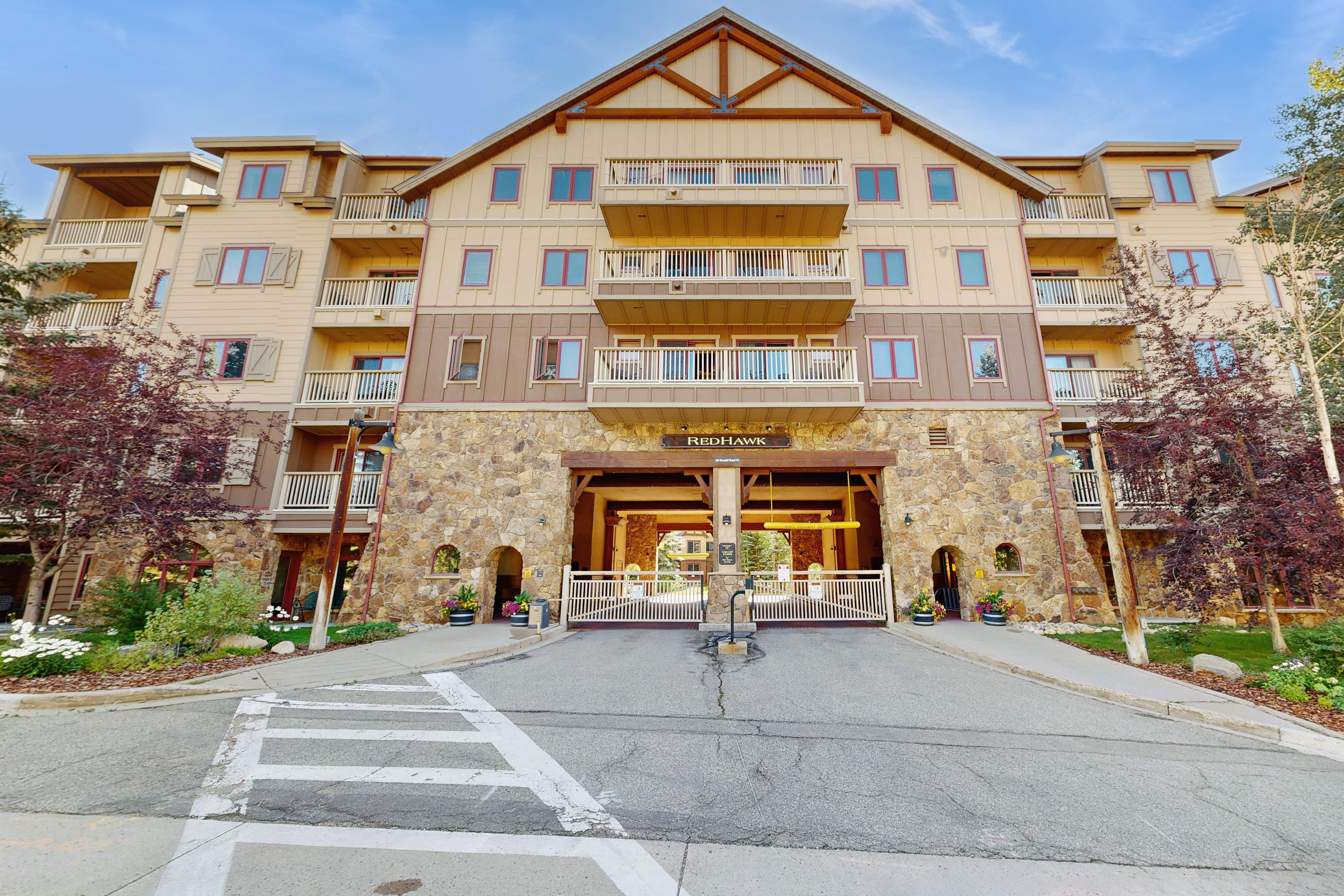 A multi-story hotel with a stone facade, balconies, and a gated entrance.