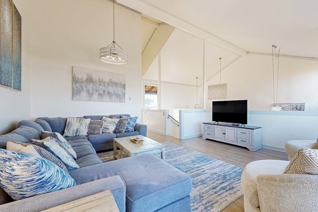 A modern living room with a sectional sofa, a flat-screen TV, and a minimalist design.