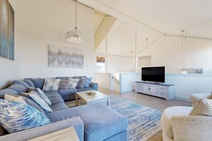 Ein modernes Wohnzimmer mit einem Ecksofa, einem Flachbildfernseher und einem minimalistischen Design.