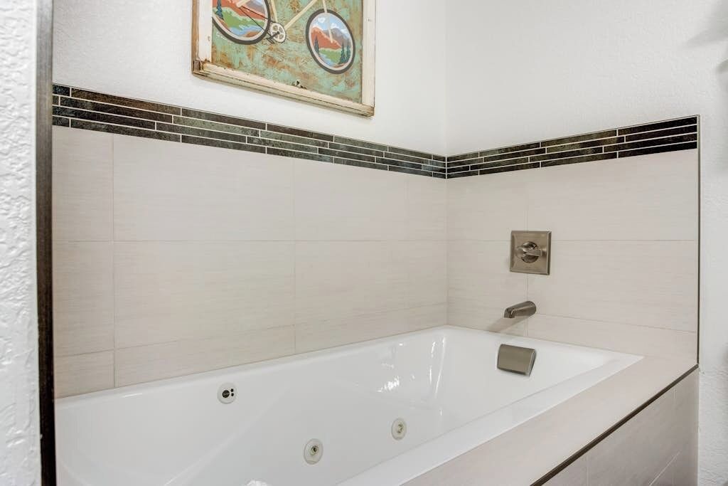 A bathroom with a large bathtub, a wall-mounted towel rack, and a framed picture above the tub.