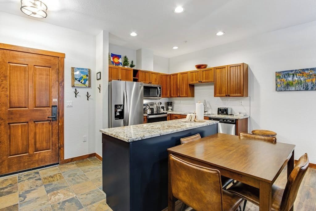 A kitchen with wooden cabinets, a stainless steel refrigerator, a microwave, and a coffee maker.
