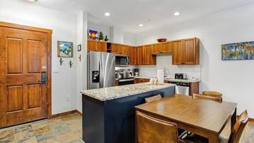 A kitchen with wooden cabinets, a stainless steel refrigerator, a microwave, and a coffee maker.