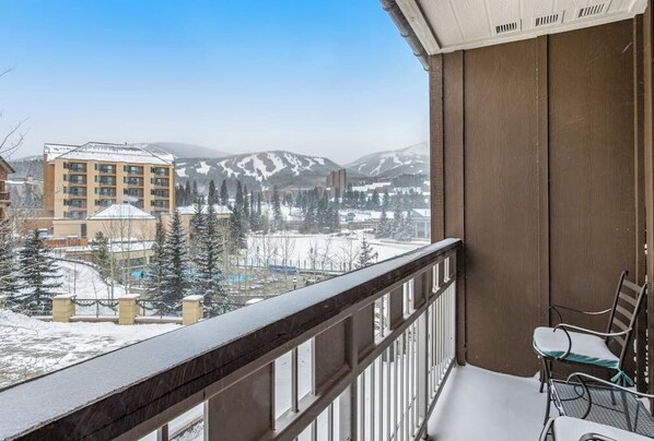 A balcony with a view of snow-covered mountains and buildings.