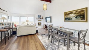 A spacious living area with a dining table, chairs, a sofa, and a fireplace.