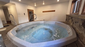 Ein Whirlpool mit Steinverkleidung, einer Holzbank und einer Steinwand.