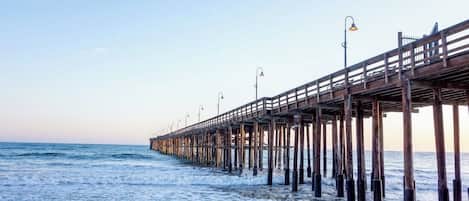 Un muelle que se adentra en el océano, con farolas y cielo despejado.