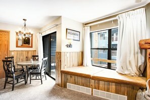 Ein gemütlicher Raum mit einer Holzbänkschrank an einem Fenster, einem Essbereich mit Stühlen, einer Chandelieber und einem Schild mit der Aufschrift 'BRECKENRIDGE'.