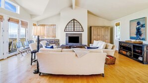 Ein geräumiges Wohnzimmer mit Kamin, weißen Sofas, einem Couchtisch und einem Bücherregal.