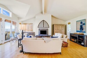 Ein geräumiges Wohnzimmer mit Kamin, weißen Sofas, einem Couchtisch und einem Bücherregal.