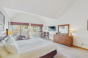 Ein Schlafzimmer mit einem großen Bett, einem Schminktisch, einem Fernseher und einem Balkon mit Blick.