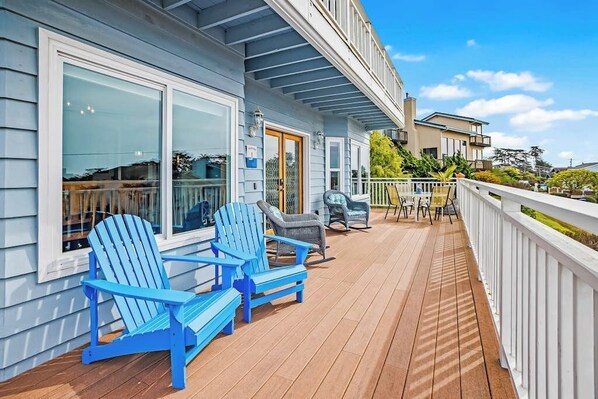 A wooden deck with Adirondack chairs, a dining table, and a white railing. - Panoramic Ocean and Sunset Views with EV Charging available (Cambria)