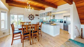 A spacious kitchen with wooden beams, a central island, and a dining area with chairs. - Panoramic Ocean and Sunset Views with EV Charging available (Cambria)