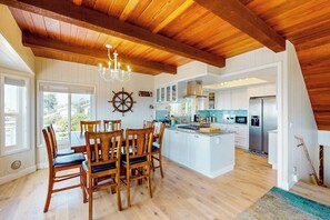 A spacious kitchen with wooden beams, a central island, and a dining area with chairs. - Panoramic Ocean and Sunset Views with EV Charging available (Cambria)