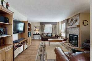 Ein Wohnzimmer mit Fernseher, Sofa, Kamin und einer Steinwand.