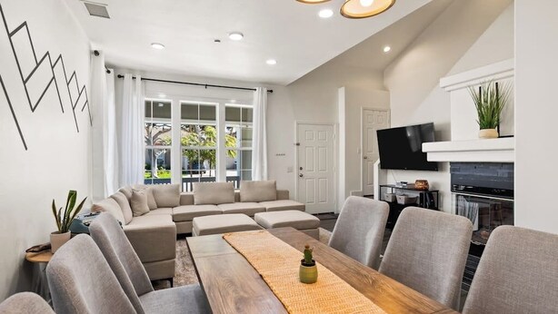 Una sala moderna con un sofá seccional, una mesa de comedor y un televisor.