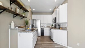 Una cocina moderna con armarios blancos, encimeras de granito y una isla central.
