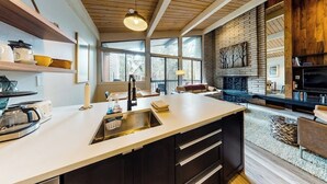 Una cocina moderna con una isla grande, techo de madera y chimenea.