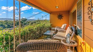Ein Balkon mit Korbmöbeln, einem Tisch und einem Wanddekor.