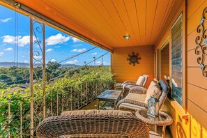 Ein Balkon mit Korbmöbeln, einem Tisch und einem Wanddekor.
