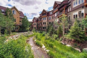 A multi-story building with balconies, a stone pathway, and surrounding greenery. - Lovely condo with pool, hot tubs & gym - next to Peak 9 lifts/downtown (Breckenridge)