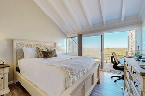 A bedroom with a bed, a desk, and a view of the outdoors. - Beachfront home with heated pool, hot tub, sports courts, amazing views, & WFH (Moss Landing)