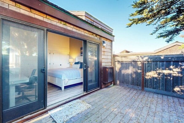 A bedroom with a sliding glass door, a bed, and a chair. - Beachfront home with heated pool, hot tub, sports courts, amazing views, & WFH (Moss Landing)