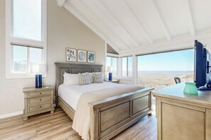Quarto com uma cama grande, mesa de cabeceira, escrivaninha e vista para o deserto.