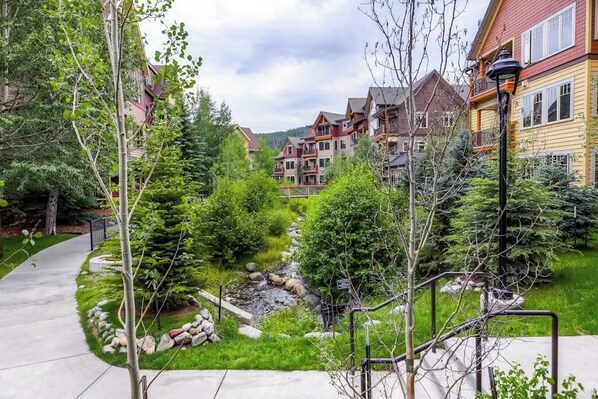 A residential area with a pathway, greenery, and multi-story buildings. - Beautiful condo with scenic views, pool, hot tubs & gym - walk to lifts/town (Breckenridge)