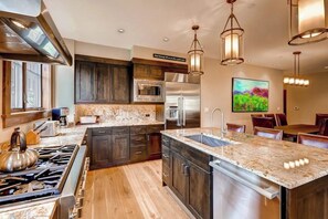 A modern kitchen with dark wood cabinets, stainless steel appliances, and a marble countertop. - Beautiful condo with scenic views, pool, hot tubs & gym - walk to lifts/town (Breckenridge)