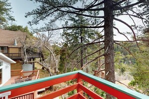 A residential property with a deck, a large tree, and a house with a balcony. - Cheery cabin with gas grill, patio, deck, outdoor space, & near lake (Lake Arrowhead)