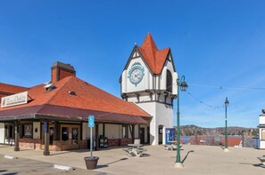 A building with a clock tower, a covered area with a sign for 'Chalet's', and a clear blue sky. - Cheery cabin with gas grill, patio, deck, outdoor space, & near lake (Lake Arrowhead)