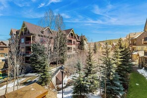 A multi-story building with balconies, surrounded by evergreen trees and a snow-covered ground. - Luxury condo with balcony, pool, hot tubs & gym - walk to lifts/downtown (Breckenridge)