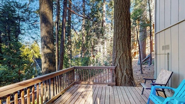 A wooden deck with a railing, surrounded by tall trees and a building. - Mountainside Retreat w/ Fireplace, BBQ & Furnished Deck - Near Village (Lake Arrowhead)