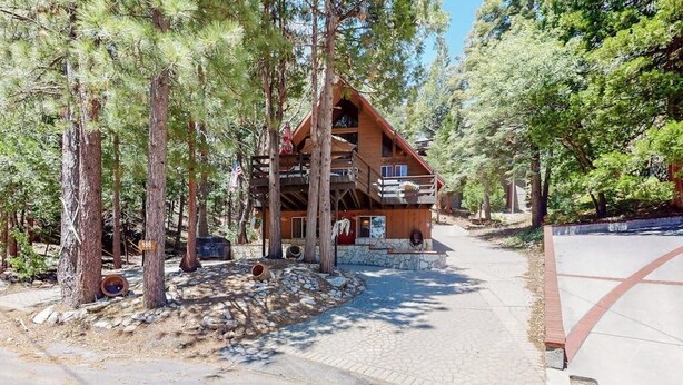 A cabin with a stone foundation, wooden exterior, and a balcony. - Cabin w/ Loft, hot tub, Fireplace, game room & Private lake trail access (Lake Arrowhead)