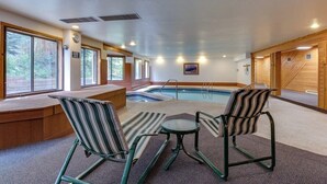 An indoor swimming pool area with two lounge chairs, a bench, and a small table. - Conveniently Located Condo with Shared Pool, Hot Tub - Walk to Slopes (Keystone)