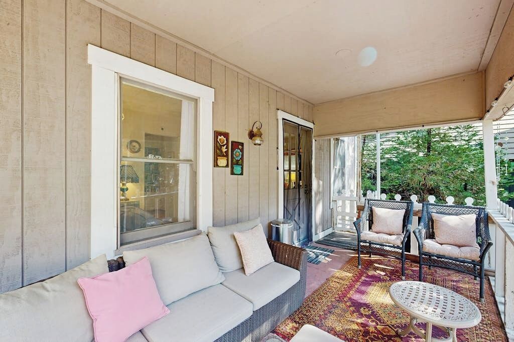 A covered porch with a sofa, chairs, and a small table.
