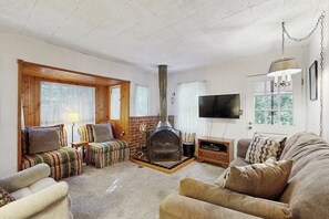A living room with a fireplace, sofas, a television, and a door with a view. - Near Lake Arrowhead Village with loft , Deck & Lake Access Card (Lake Arrowhead)