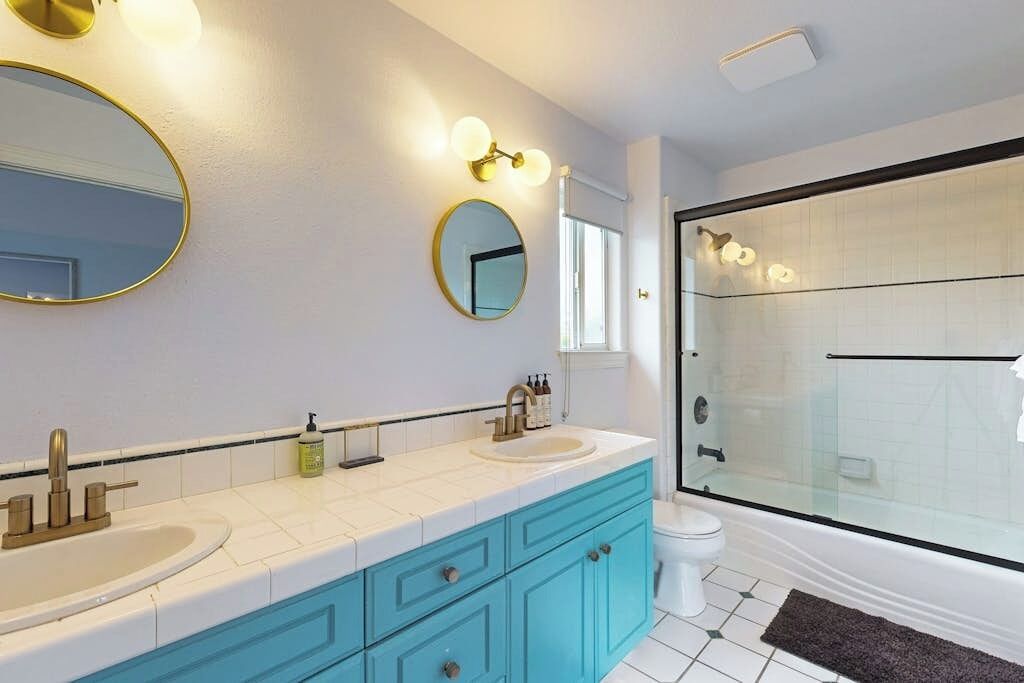 Een badkamer met twee wasbakken, een spiegel en een douche met glazen wanden.