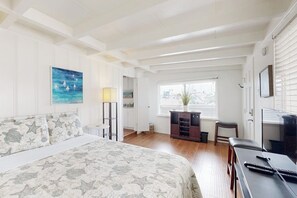Ein Schlafzimmer mit einem Bett, einem Schreibtisch, einem Stuhl, einer Lampe, einem Fenster und einem Bild an der Wand.