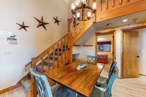Ein Essbereich mit Holztisch und Stühlen, einer Treppe und einer Kandelaber.