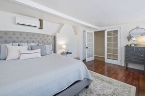 A bedroom with a large bed, a nightstand, a dresser, and a white door leading to another room. - Downtown home w/private hot tub, pool table, gas grill, W/D, AC (Paso Robles)
