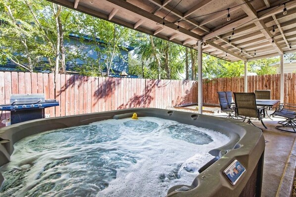 A hot tub under a covered patio with a wooden fence, outdoor furniture, and a grill. - Downtown home w/private hot tub, pool table, gas grill, W/D, AC (Paso Robles)
